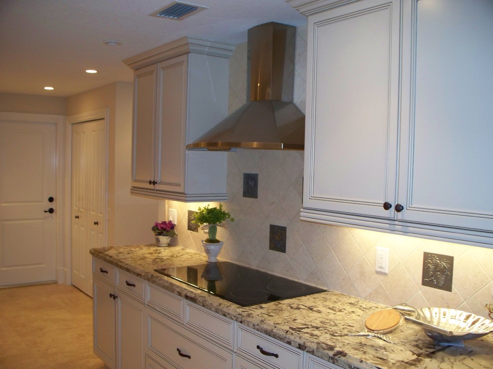 Large traditional u-shaped eat-in kitchen in Miami with a double-bowl sink, recessed-panel cabinets, white cabinets, granite benchtops, beige splashback, ceramic splashback, stainless steel appliances, porcelain floors and a peninsula.