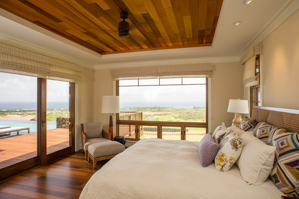 Photo of a tropical master bedroom in Hawaii with beige walls and medium hardwood floors.