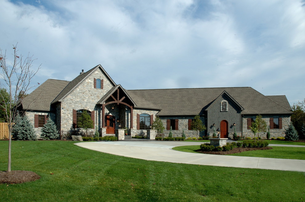 Large country two-storey grey house exterior in Cleveland with stone veneer, a hip roof and a shingle roof.