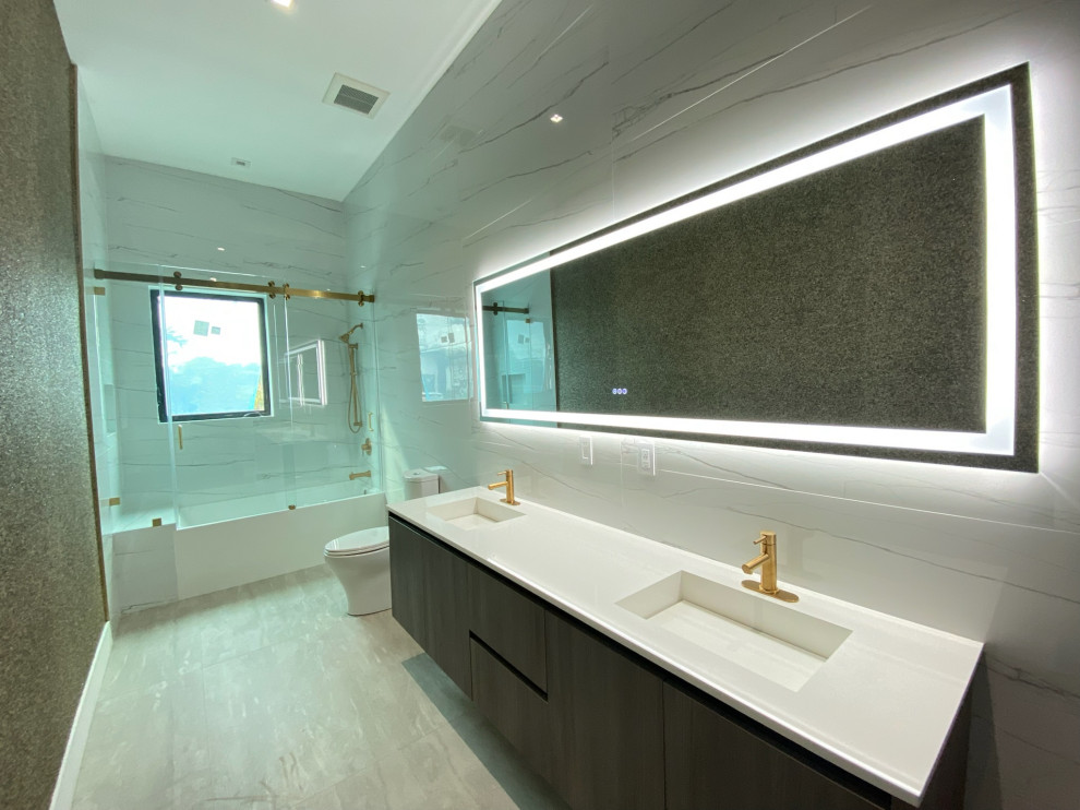 Пример оригинального дизайна: серо-белая ванная комната среднего размера в стиле модернизм с душем над ванной, тумбой под две раковины, напольной тумбой, плоскими фасадами, ванной в нише, унитазом-моноблоком, разноцветной плиткой, мраморной плиткой, разноцветными стенами, полом из мозаичной плитки, душевой кабиной, накладной раковиной, столешницей из гранита, разноцветным полом, душем с распашными дверями, белой столешницей, зеркалом с подсветкой и многоуровневым потолком