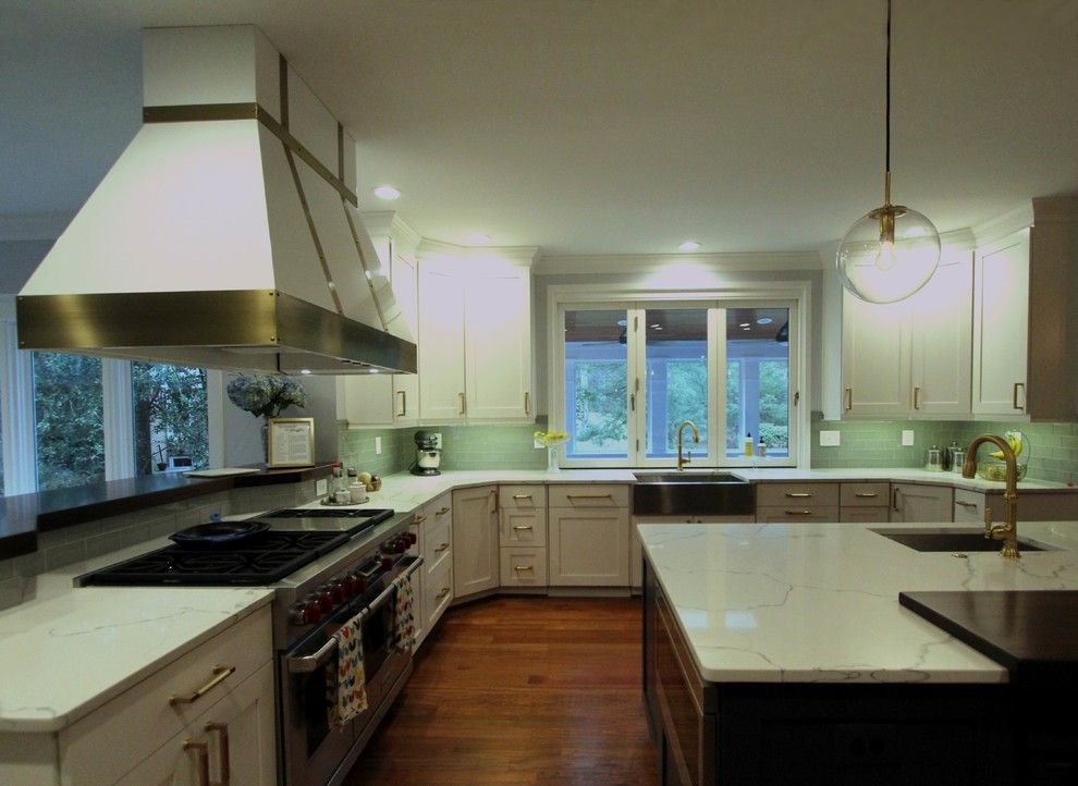 This is an example of an expansive transitional u-shaped eat-in kitchen in DC Metro with a farmhouse sink, flat-panel cabinets, blue cabinets, quartzite benchtops, green splashback, glass tile splashback, stainless steel appliances, medium hardwood floors, with island and red floor.