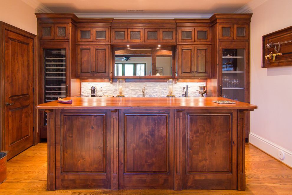 Design ideas for a traditional single-wall seated home bar in Other with dark wood cabinets, wood benchtops and medium hardwood floors.