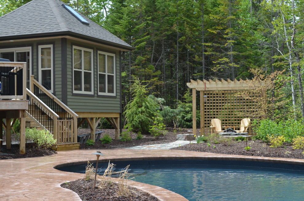 Example of a large mountain style backyard stamped concrete and freeform natural pool design