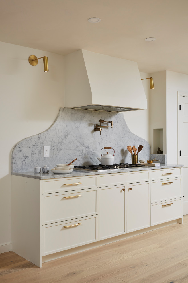 Idéer för ett mellanstort modernt vit kök, med en undermonterad diskho, skåp i shakerstil, skåp i ljust trä, marmorbänkskiva, vitt stänkskydd, stänkskydd i marmor, rostfria vitvaror, ljust trägolv, en köksö och beiget golv