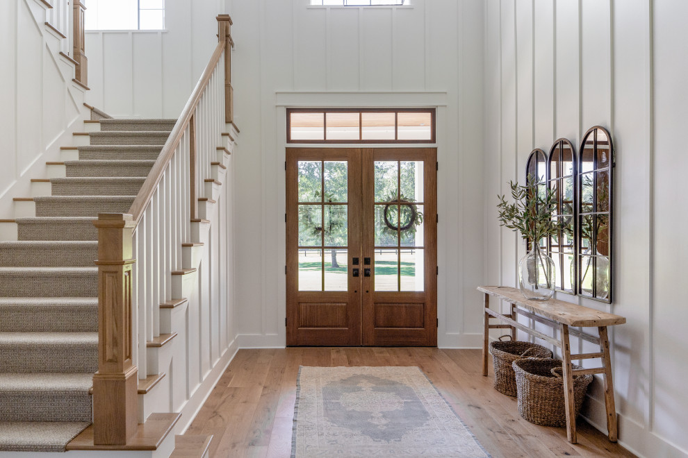 Idée de décoration pour un grand hall d'entrée champêtre en bois avec un mur blanc, un sol marron, un sol en bois brun, une porte double et une porte en bois foncé.