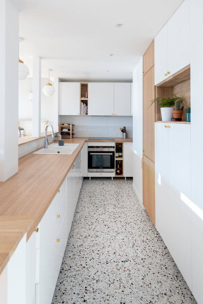 Diseño de cocina lineal escandinava pequeña con armarios con rebordes decorativos, puertas de armario blancas, encimera de madera, salpicadero blanco, salpicadero de azulejos de cerámica y suelo de terrazo