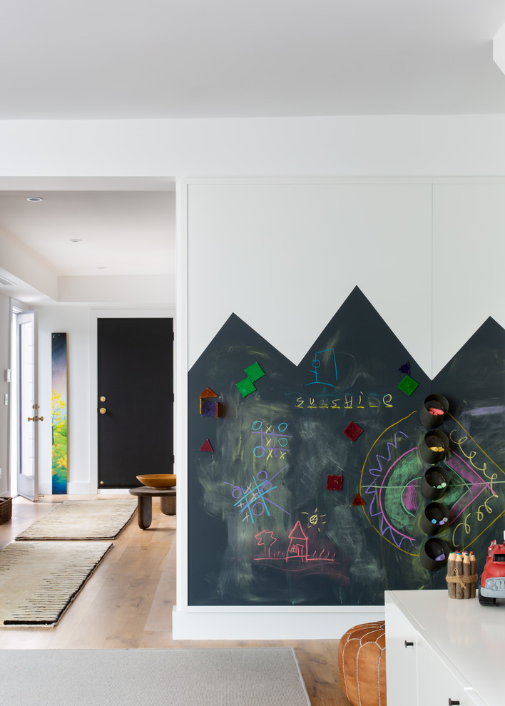Pacific Heights Collected Contemporary - Intentional. Elevated. Artisanal.
 
With three children under the age of 5, our clients were starting to feel the confines of their Pacific Heights home when the expansive 1902 Italianate across the street went on the market. After learning the home had been recently remodeled, they jumped at the chance to purchase a move-in ready property. We worked with them to infuse the already refined, elegant living areas with subtle edginess and handcrafted details, and also helped them reimagine unused space to delight their little ones.
 
Elevated furnishings on the main floor complement the home’s existing high ceilings, modern brass bannisters and extensive walnut cabinetry. In the living room, sumptuous emerald upholstery on a velvet side chair balances the deep wood tones of the existing baby grand. Minimally and intentionally accessorized, the room feels formal but still retains a sharp edge—on the walls moody portraiture gets irreverent with a bold paint stroke, and on the the etagere, jagged crystals and metallic sculpture feel rugged and unapologetic. Throughout the main floor handcrafted, textured notes are everywhere—a nubby jute rug underlies inviting sofas in the family room and a half-moon mirror in the living room mixes geometric lines with flax-colored fringe. 
 
On the home’s lower level, we repurposed an unused wine cellar into a well-stocked craft room, with a custom chalkboard, art-display area and thoughtful storage. In the adjoining space, we installed a custom climbing wall and filled the balance of the room with low sofas, plush area rugs, poufs and storage baskets, creating the perfect space for active play or a quiet reading session. The bold colors and playful attitudes apparent in these spaces are echoed upstairs in each of the children’s imaginative bedrooms.
 
Architect + Developer: McMahon Architects + Studio, Photographer: Suzanna Scott Photography