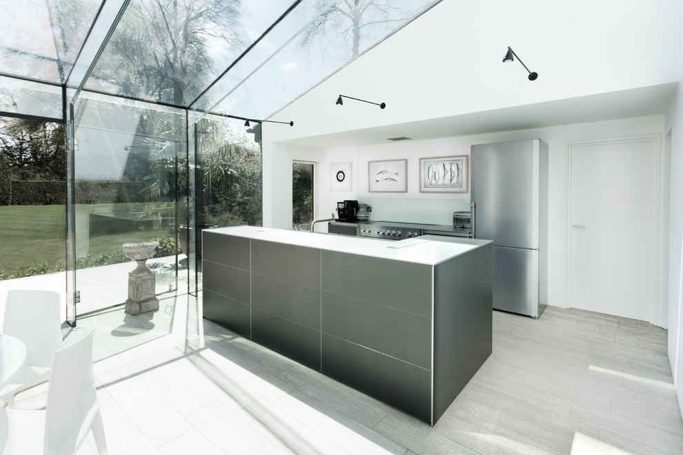 This is an example of a mid-sized modern single-wall kitchen in Hampshire with flat-panel cabinets, grey cabinets, quartzite benchtops, glass sheet splashback, stainless steel appliances, with island, grey floor and white benchtop.