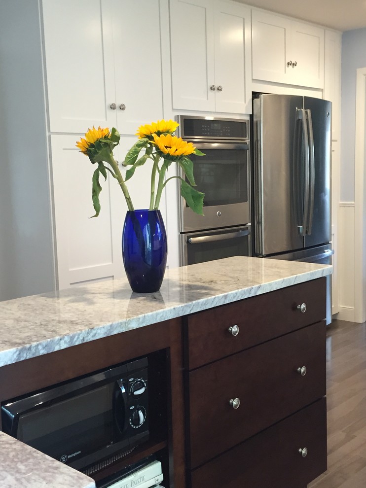 Enclosed kitchen - mid-sized transitional l-shaped medium tone wood floor enclosed kitchen idea in Providence with an undermount sink, shaker cabinets, white cabinets, marble countertops, stainless steel appliances and a peninsula