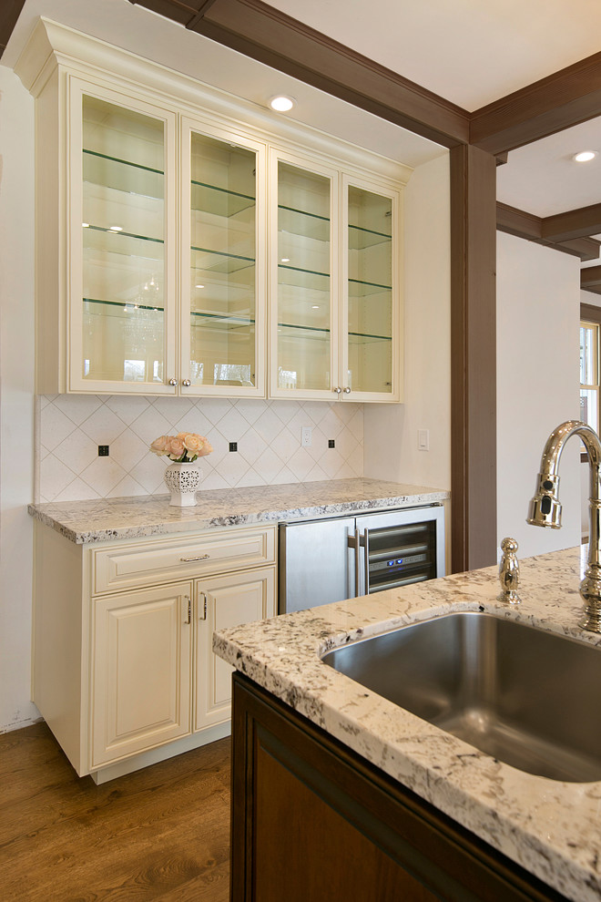 Inspiration for a large traditional l-shaped eat-in kitchen in San Francisco with an undermount sink, raised-panel cabinets, white cabinets, granite benchtops, white splashback, stone tile splashback, stainless steel appliances, medium hardwood floors, with island, brown floor and multi-coloured benchtop.