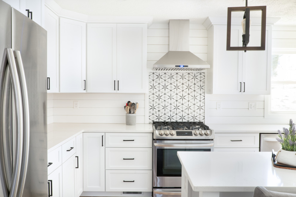 Design ideas for a mid-sized beach style l-shaped kitchen pantry in Baltimore with an undermount sink, shaker cabinets, white cabinets, quartz benchtops, white splashback, shiplap splashback, stainless steel appliances, medium hardwood floors, with island, brown floor and white benchtop.