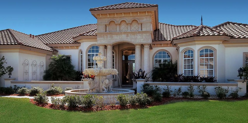 This is an example of a mid-sized mediterranean one-storey stucco beige house exterior in Orlando with a hip roof and a tile roof.
