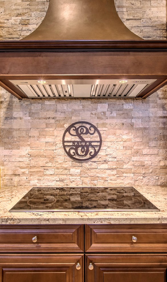 Large transitional l-shaped brown floor open concept kitchen photo in Phoenix with a double-bowl sink, raised-panel cabinets, dark wood cabinets, granite countertops, beige backsplash, stone tile backsplash, stainless steel appliances and an island