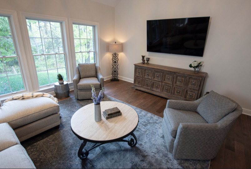 На фото: гостиная комната среднего размера с бежевыми стенами, темным паркетным полом, телевизором на стене и коричневым полом с