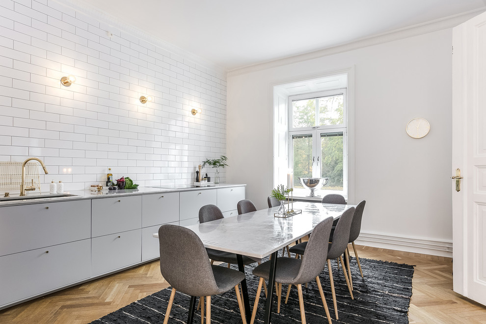 Inspiration for a large scandinavian single-wall eat-in kitchen in Malmo with grey cabinets, marble benchtops, white splashback, no island, an undermount sink, flat-panel cabinets, subway tile splashback and light hardwood floors.
