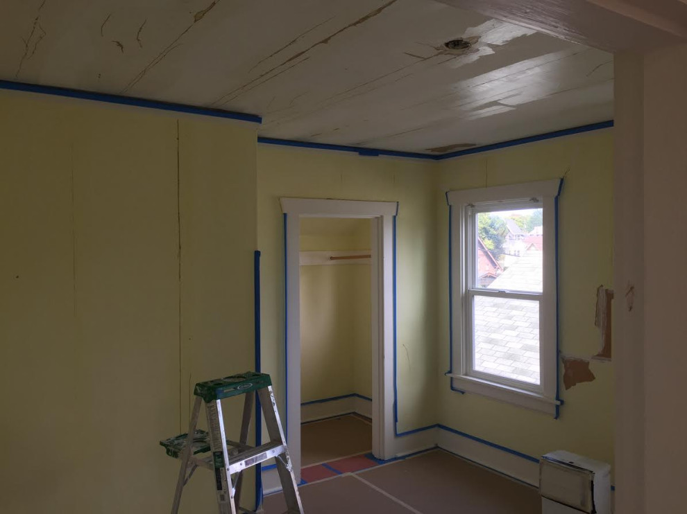 Aménagement d'une chambre d'amis craftsman de taille moyenne avec un mur jaune, un sol en bois brun, un sol rouge et du papier peint.