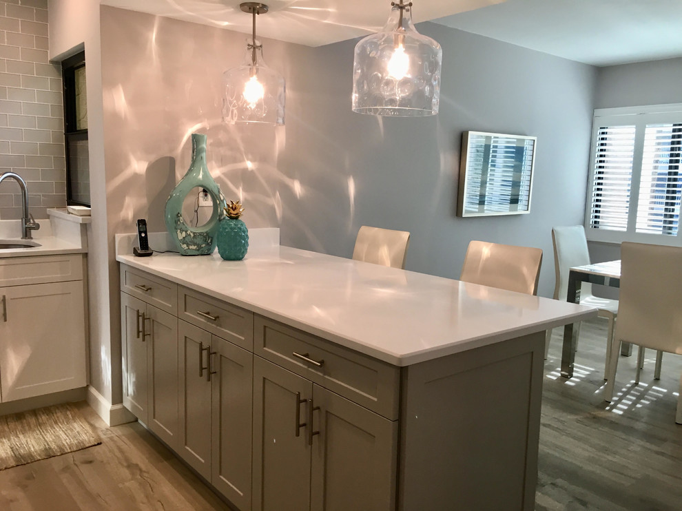 Design ideas for a small beach style galley eat-in kitchen in Tampa with an undermount sink, shaker cabinets, grey cabinets, quartzite benchtops, glass tile splashback, stainless steel appliances, vinyl floors, a peninsula, grey floor and white benchtop.