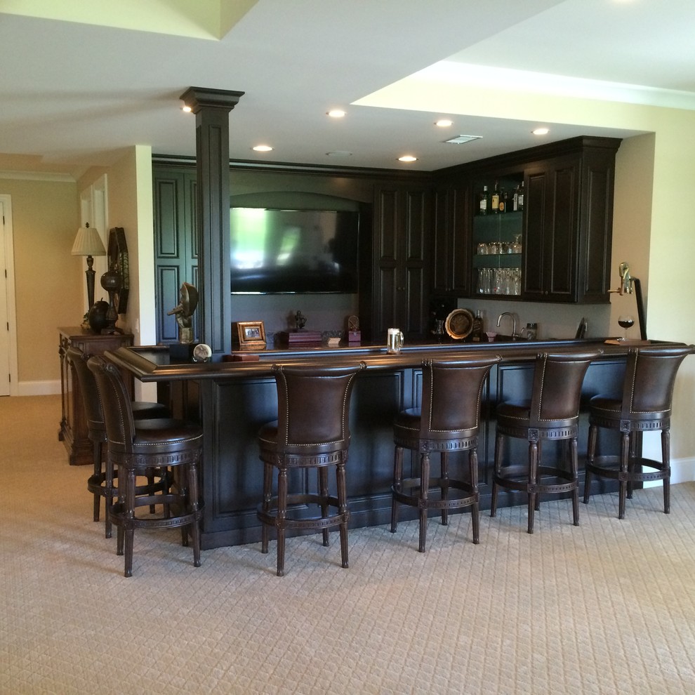 Large traditional l-shaped wet bar in Chicago with raised-panel cabinets, dark wood cabinets, quartz benchtops and porcelain floors.