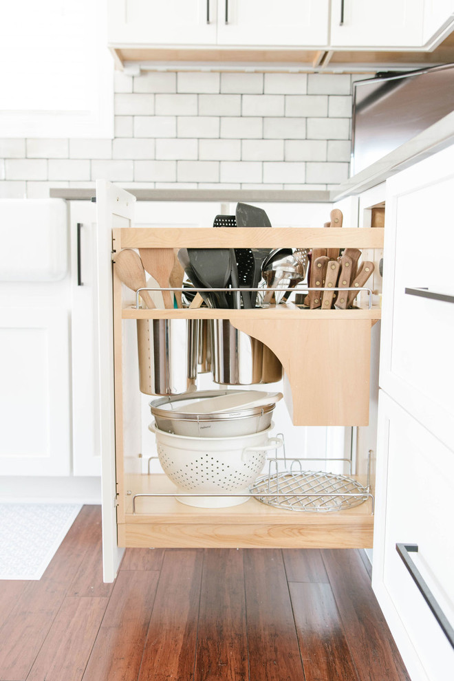 Mid-sized transitional l-shaped medium tone wood floor and brown floor eat-in kitchen photo in Omaha with a farmhouse sink, shaker cabinets, white cabinets, quartzite countertops, white backsplash, subway tile backsplash, stainless steel appliances, an island and white countertops