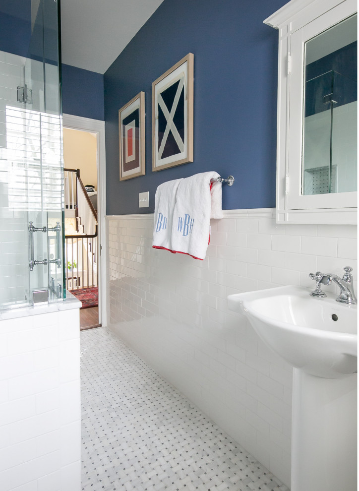 Small traditional family bathroom in Baltimore with white cabinets, a two-piece toilet, blue tiles, ceramic tiles, blue walls, marble flooring, a pedestal sink, white floors, a hinged door, a wall niche, double sinks, a freestanding vanity unit and wainscoting.