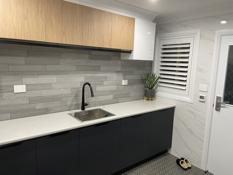 Photo of a medium sized contemporary l-shaped separated utility room in Other with a built-in sink, flat-panel cabinets, laminate countertops and a side by side washer and dryer.