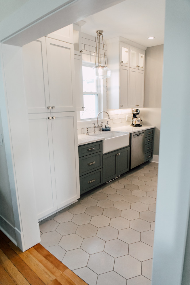 This is an example of a small country galley separate kitchen in Seattle with a farmhouse sink, shaker cabinets, grey cabinets, quartz benchtops, white splashback, ceramic splashback, stainless steel appliances, porcelain floors, grey floor and white benchtop.