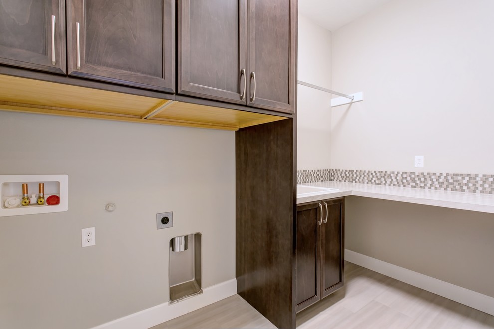Mid-sized transitional l-shaped porcelain tile and gray floor home design photo in Seattle with a double-bowl sink, recessed-panel cabinets, dark wood cabinets, laminate countertops, gray walls, a side-by-side washer/dryer and white countertops