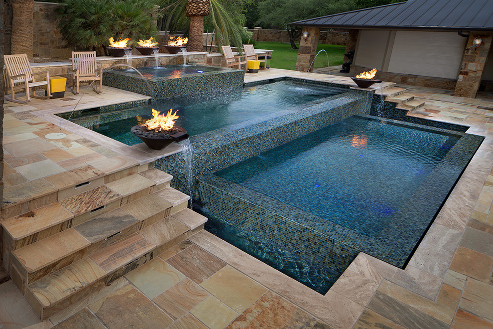 This is an example of a mid-sized contemporary backyard rectangular infinity pool in Austin with natural stone pavers.