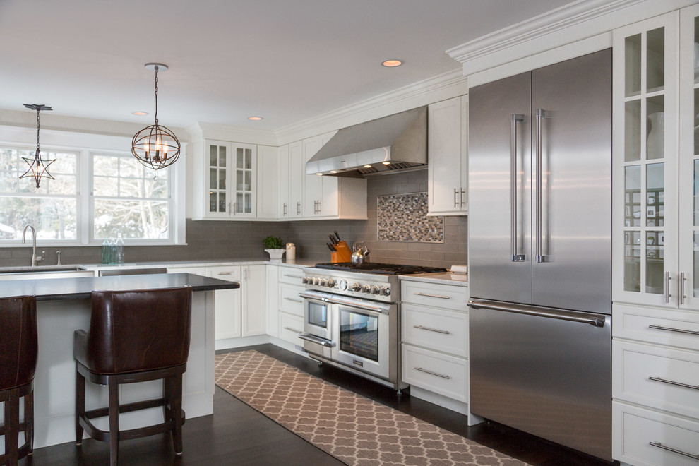 Large transitional l-shaped dark wood floor and brown floor eat-in kitchen photo in Boston with a farmhouse sink, recessed-panel cabinets, white cabinets, marble countertops, green backsplash, ceramic backsplash, stainless steel appliances, an island and white countertops