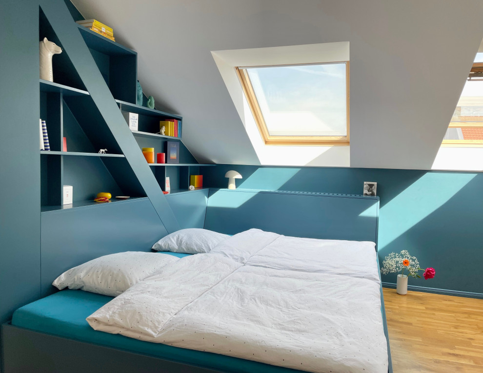 Mittelgroßes Modernes Schlafzimmer mit blauer Wandfarbe, hellem Holzboden, braunem Boden und freigelegten Dachbalken in Berlin