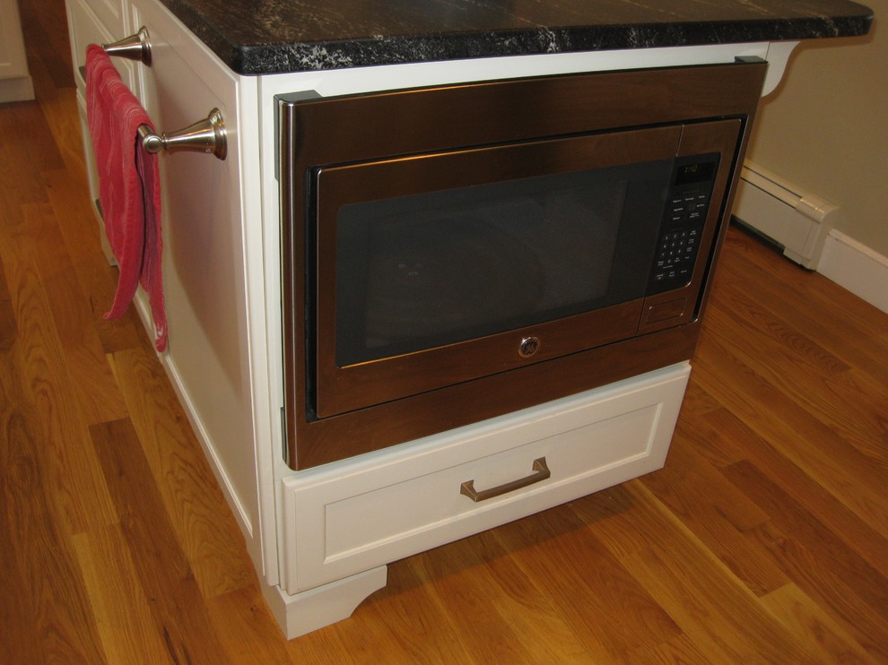 Eat-in kitchen - transitional l-shaped medium tone wood floor eat-in kitchen idea in Boston with an undermount sink, shaker cabinets, white cabinets, quartz countertops, white backsplash, ceramic backsplash, stainless steel appliances, an island and black countertops