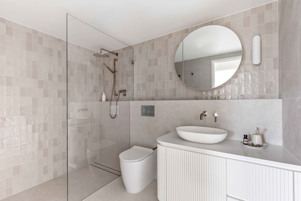 Inredning av ett modernt mellanstort vit vitt badrum med dusch, med vita skåp, en kantlös dusch, en vägghängd toalettstol, grå kakel, porslinskakel, grå väggar, klinkergolv i porslin, ett fristående handfat, bänkskiva i kvarts, grått golv och med dusch som är öppen