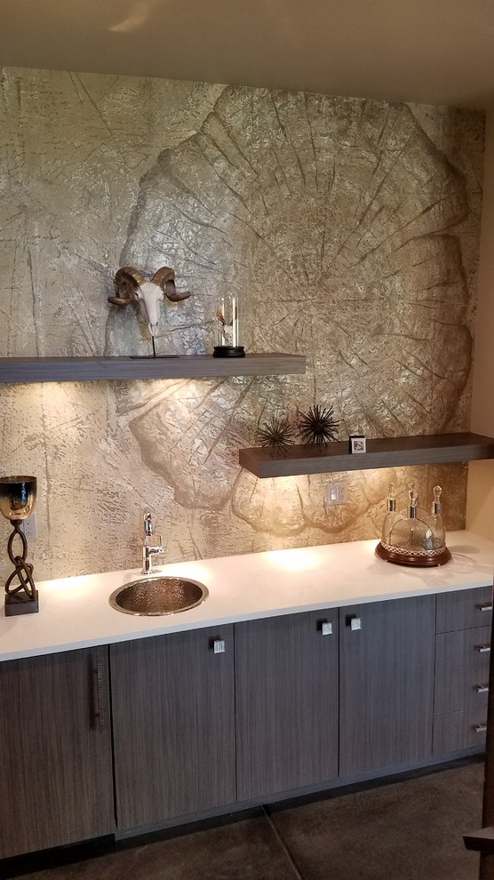 Inspiration for a mid-sized traditional single-wall wet bar in Denver with a drop-in sink, black cabinets, solid surface benchtops, multi-coloured splashback, brown floor and white benchtop.