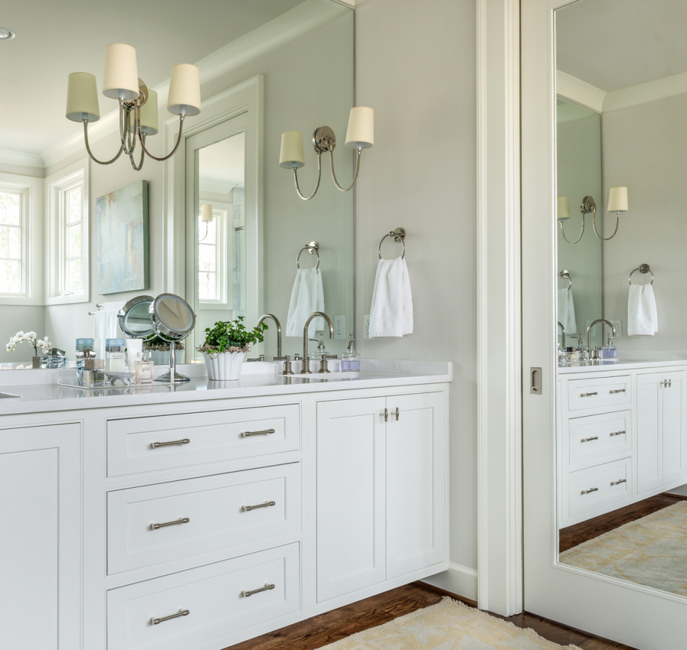 Design ideas for a large transitional master bathroom in Birmingham with shaker cabinets, white cabinets, grey walls, medium hardwood floors, an undermount sink, brown floor and white benchtops.