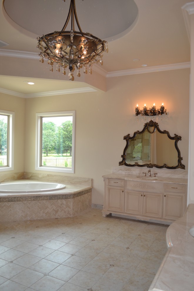 Design ideas for a mediterranean master bathroom in Dallas with raised-panel cabinets, beige cabinets, a corner tub, beige tile, cement tile, beige walls and laminate benchtops.