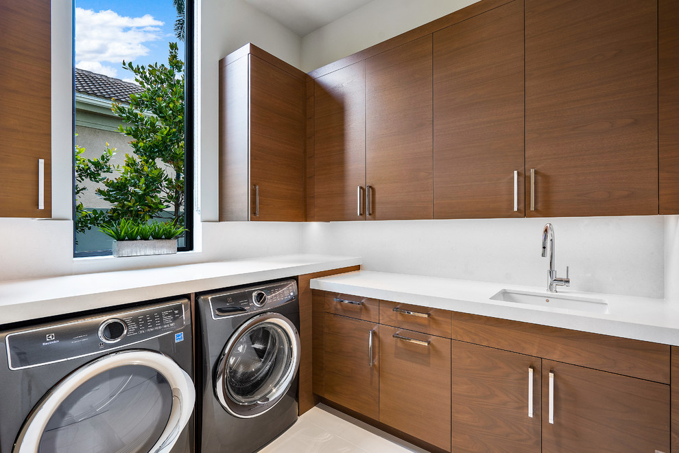 Design ideas for a large contemporary l-shaped dedicated laundry room in Miami with an undermount sink, flat-panel cabinets, medium wood cabinets, white walls, marble floors, a side-by-side washer and dryer, white floor and white benchtop.