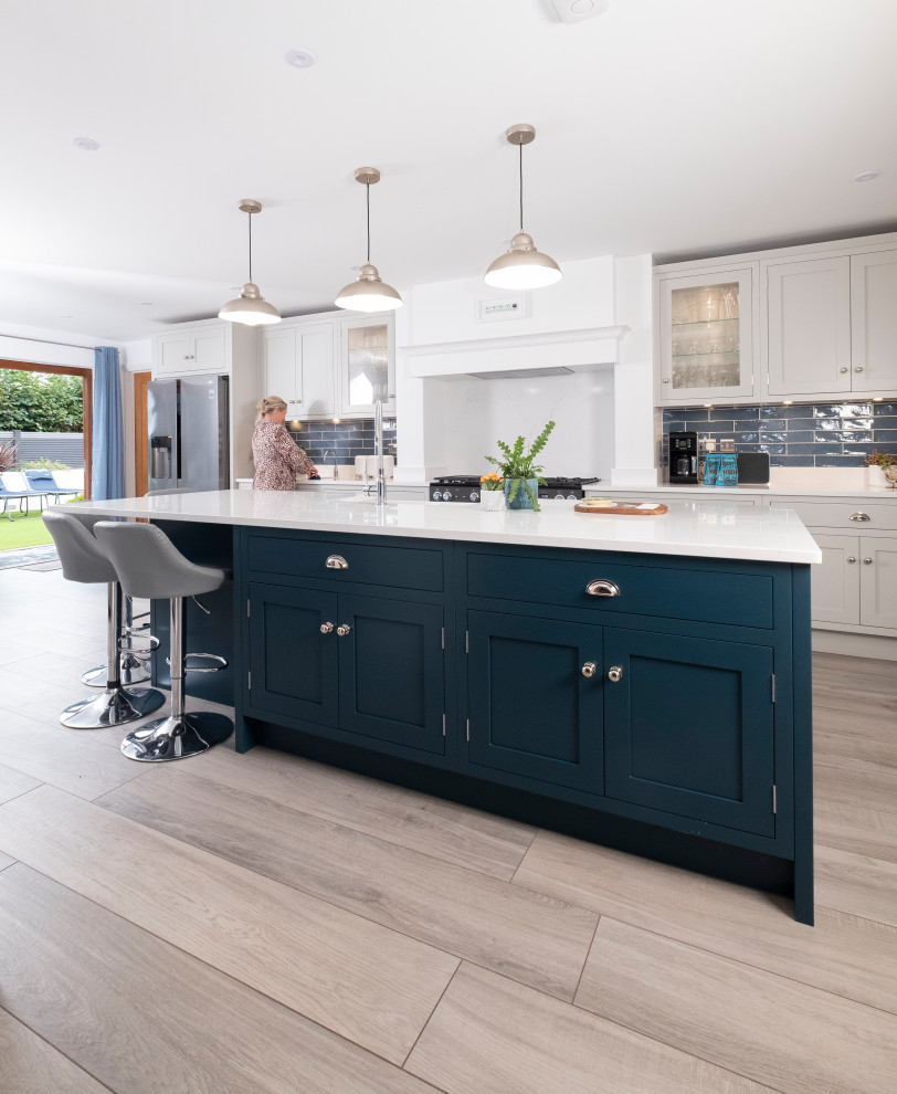 Photo of a large traditional single-wall open plan kitchen in Other with a drop-in sink, shaker cabinets, quartzite benchtops, blue splashback, ceramic splashback, laminate floors, with island and white benchtop.