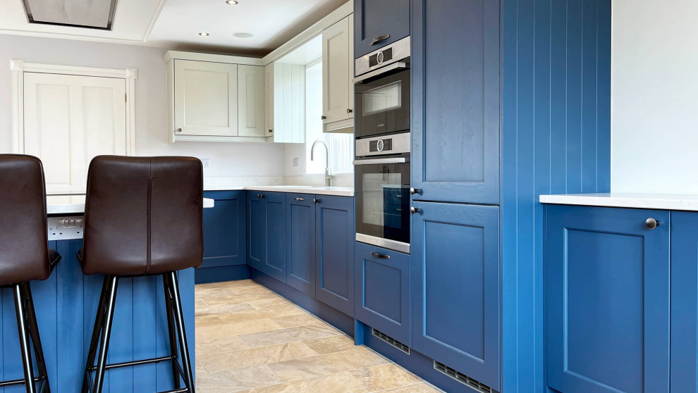Large traditional single-wall open plan kitchen in Other with a double-bowl sink, shaker cabinets, blue cabinets, quartz worktops, white splashback, black appliances, ceramic flooring, an island, multi-coloured floors, white worktops and a drop ceiling.