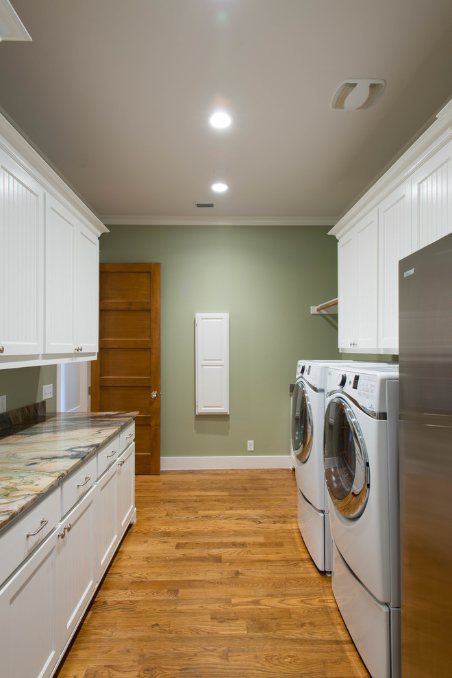 This is an example of a large arts and crafts galley utility room in Dallas with an undermount sink, shaker cabinets, white cabinets, quartzite benchtops, green walls, medium hardwood floors and a side-by-side washer and dryer.