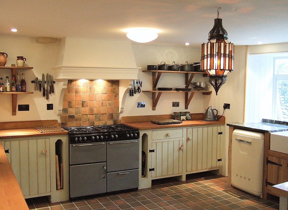 Photo of a large country u-shaped eat-in kitchen in Wiltshire with a double-bowl sink, beaded inset cabinets, green cabinets, granite benchtops, brown splashback, terra-cotta splashback, coloured appliances, ceramic floors and no island.
