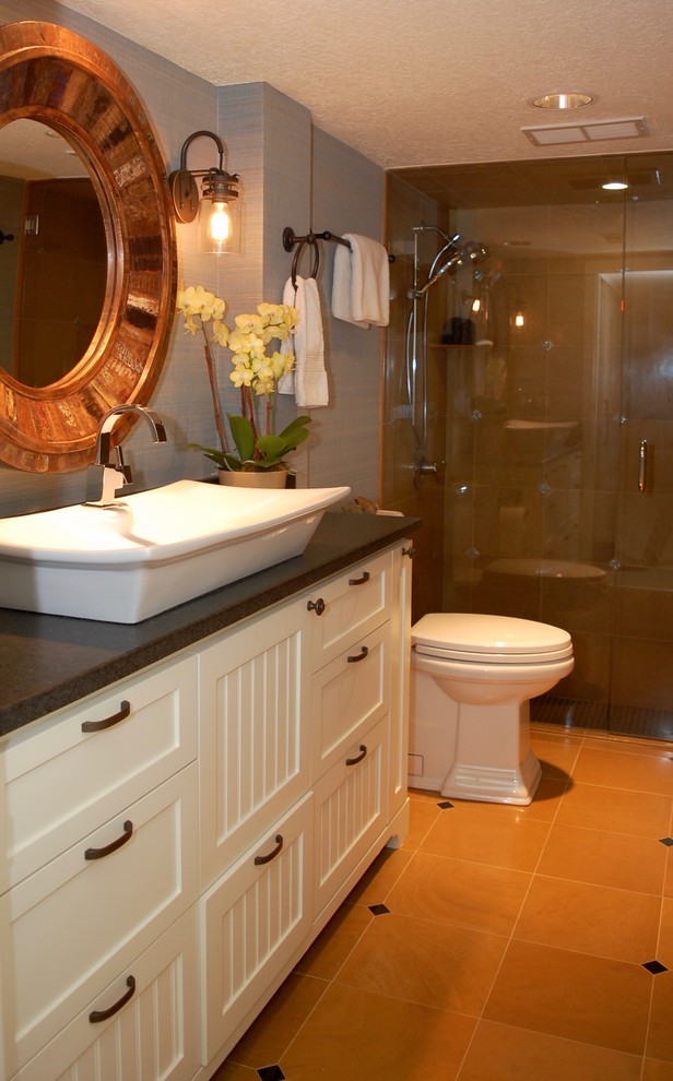 Photo of a small transitional bathroom in Portland with beaded inset cabinets, white cabinets, an alcove shower, a one-piece toilet, orange tile, ceramic tile, a vessel sink, granite benchtops, a hinged shower door and black benchtops.