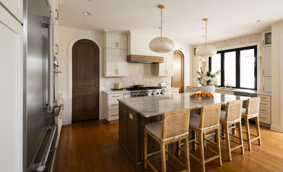 Example of a transitional u-shaped medium tone wood floor and brown floor kitchen design in Chicago with an undermount sink, shaker cabinets, beige cabinets, gray backsplash, stone slab backsplash, stainless steel appliances, an island and gray countertops