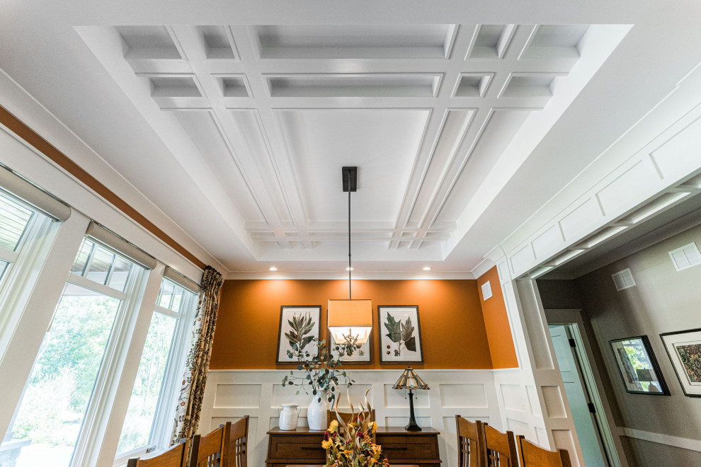 На фото: столовая среднего размера в стиле кантри с оранжевыми стенами, паркетным полом среднего тона, коричневым полом, кессонным потолком и панелями на стенах с
