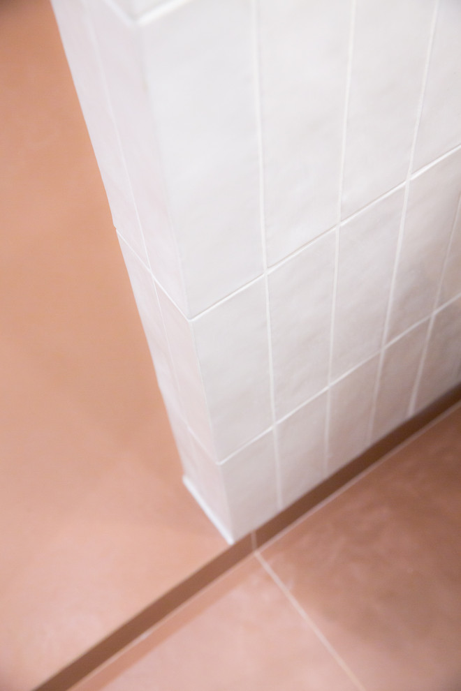 Bild på ett litet maritimt vit vitt badrum med dusch, med luckor med infälld panel, skåp i ljust trä, en kantlös dusch, vit kakel, porslinskakel, rosa väggar, klinkergolv i keramik, ett konsol handfat, bänkskiva i akrylsten, orange golv och med dusch som är öppen