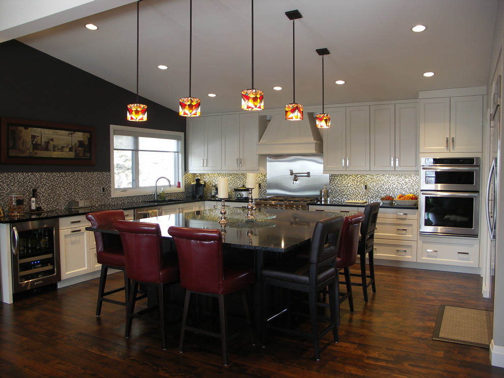 Mid-sized transitional l-shaped medium tone wood floor kitchen photo in Edmonton with an undermount sink, shaker cabinets, white cabinets, granite countertops, metallic backsplash, stainless steel appliances and an island