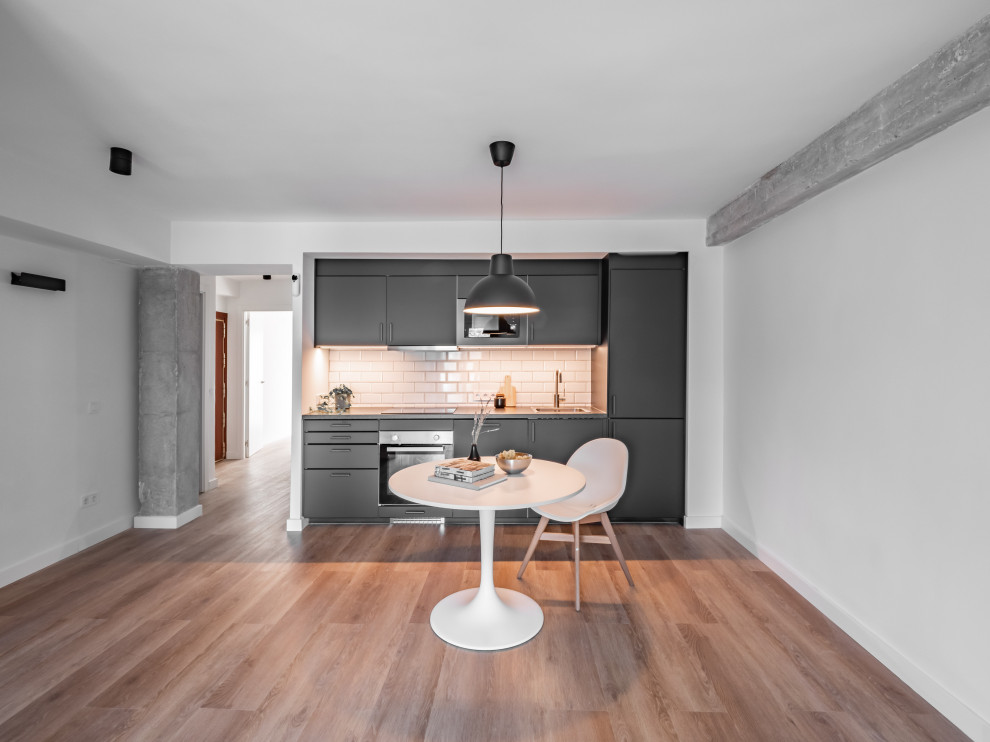 Photo of a small industrial single-wall open plan kitchen in Madrid with a single-bowl sink, flat-panel cabinets, grey cabinets, laminate benchtops, white splashback, subway tile splashback, panelled appliances, laminate floors, no island, brown floor, grey benchtop and exposed beam.