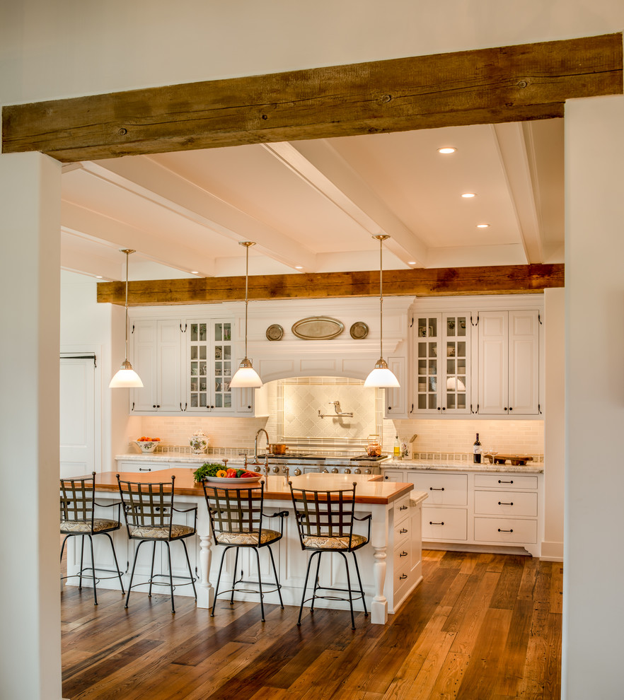 This is an example of an expansive country galley eat-in kitchen in Philadelphia with raised-panel cabinets, white cabinets, white splashback, stone tile splashback, stainless steel appliances, marble benchtops, medium hardwood floors, with island, a farmhouse sink and brown floor.