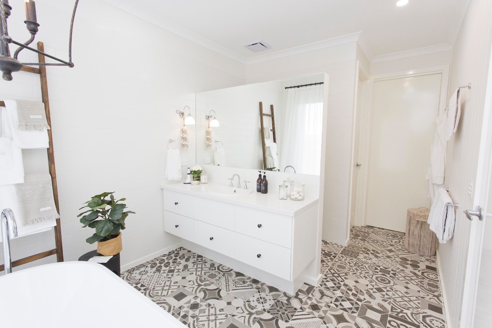 Photo of a beach style bathroom in Melbourne with flat-panel cabinets, white cabinets, a freestanding tub, gray tile, white walls, a drop-in sink and an open shower.