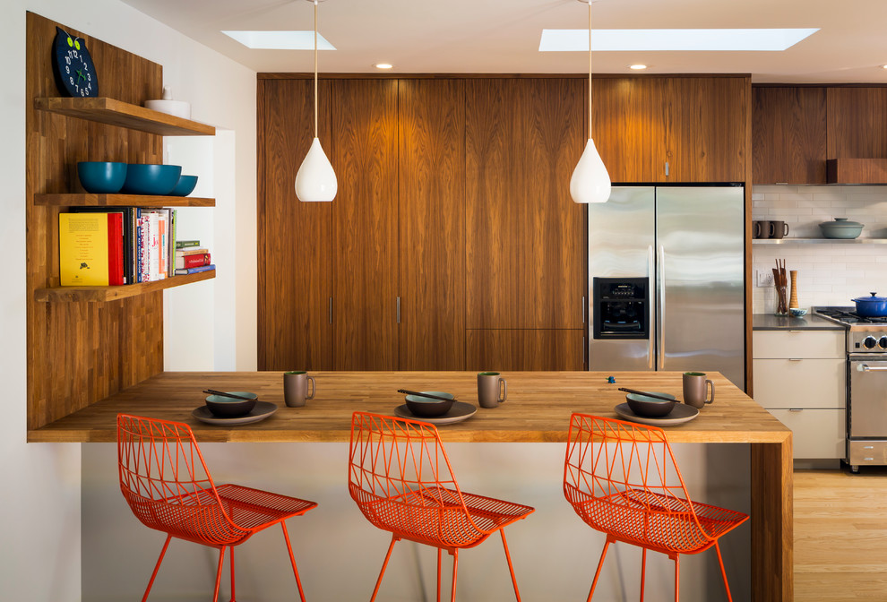 Mid-sized contemporary u-shaped eat-in kitchen in San Francisco with flat-panel cabinets, dark wood cabinets, white splashback, stainless steel appliances, wood benchtops, subway tile splashback, an undermount sink, medium hardwood floors and a peninsula.