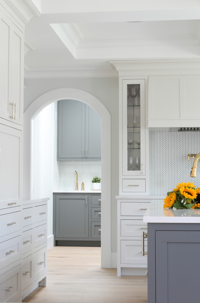 Inspiration for a large transitional l-shaped eat-in kitchen in Vancouver with an undermount sink, shaker cabinets, white cabinets, quartz benchtops, white splashback, mosaic tile splashback, panelled appliances, light hardwood floors, with island, white benchtop and coffered.